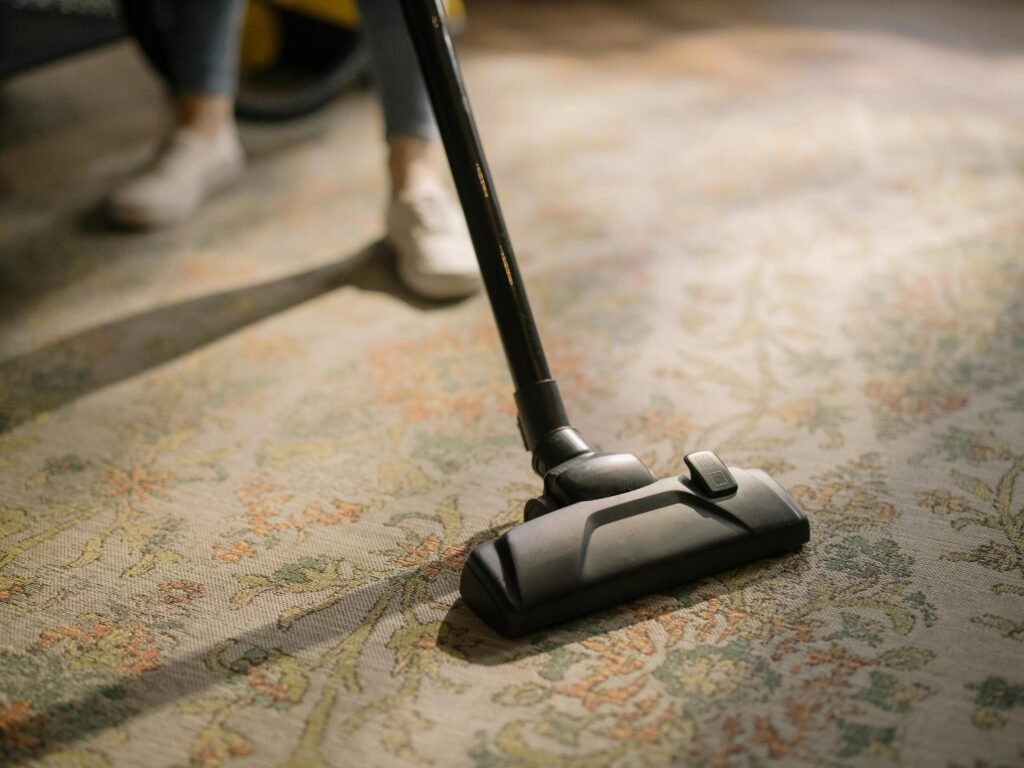 red Persian rugs, Afghanistan Rugs, Afghan Rugs, Persian Rugs, Oriental Rugs, Close-up of a vacuum cleaner on a patterned carpet in a sunlit room, capturing a moment of household cleaning.